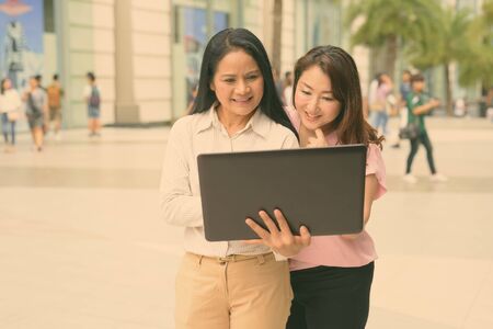 Two mature Asian women together outside the mall in Bangkok cityの写真素材