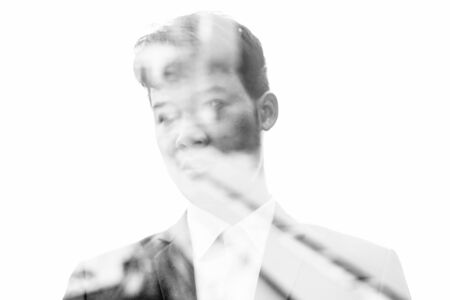 Portrait of young Asian businessman against view of the city in black and whiteの写真素材