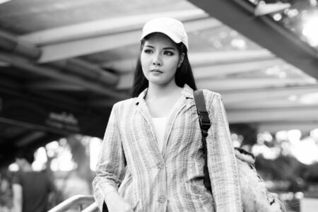 Portrait of young beautiful Asian tourist woman exploring the city in black and white