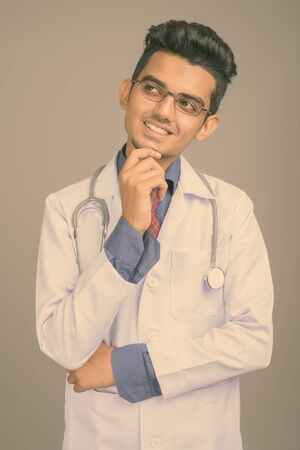 Young Indian man doctor against gray backgroundの写真素材