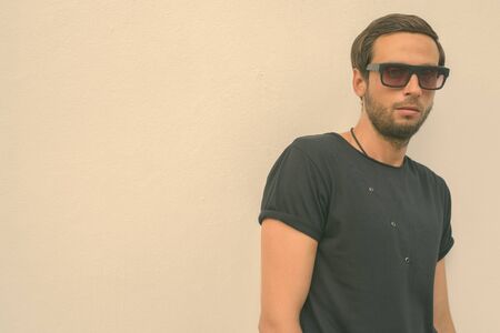 Handsome man wearing black shirt and sunglasses against white background