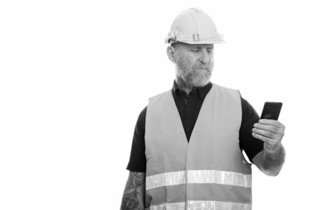 Mature bearded man construction worker using phoneの写真素材