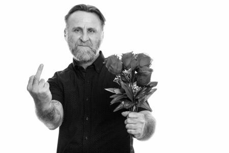 Studio shot of mature bearded man holding roses while showing his middle fingerの写真素材