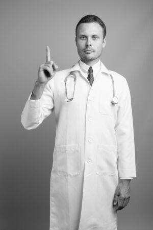 Portrait of handsome man doctor against gray backgroundの写真素材