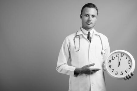 Portrait of handsome man doctor against gray backgroundの写真素材