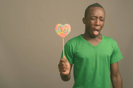 Young African man wearing green shirt against gray backgroundの写真素材