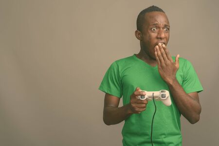 Young African man wearing green shirt against gray background