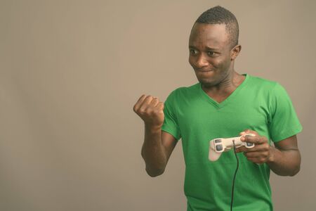 Young African man wearing green shirt against gray background