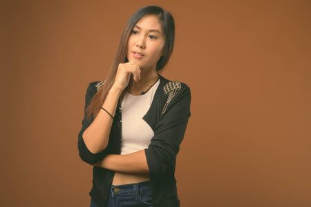 Young beautiful Asian woman against brown background