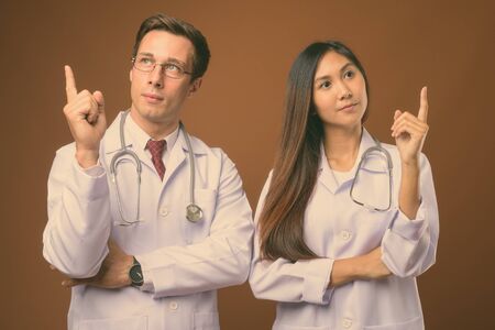 Studio shot of two young doctors together against brown backgroundの写真素材