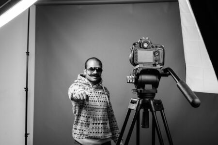 Indian man with mustache vlogging against gray background