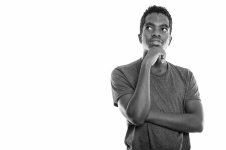 Studio shot of young black African teenage boy thinking while looking upの写真素材