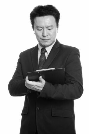 Studio shot of Japanese businessman reading on clipboardの写真素材