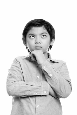 Studio shot of cute Japanese boy thinking while looking upの写真素材