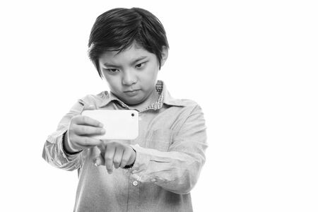 Studio shot of cute Japanese boy taking picture with mobile phoneの写真素材