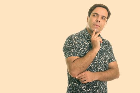 Studio shot of young Persian man thinking isolated against white backgroundの写真素材