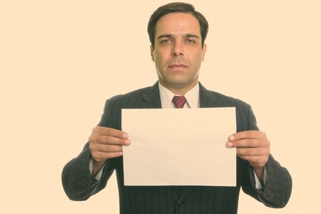 Studio shot of young Persian businessman holding paper isolated against white background