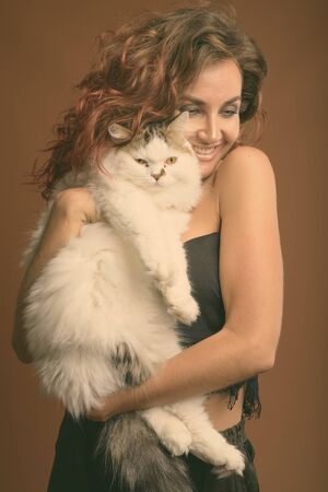 Young beautiful woman with curly hair against brown backgroundの写真素材