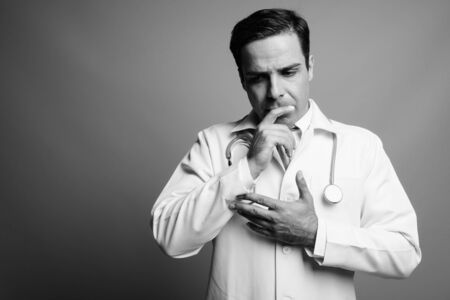 Handsome Persian man doctor against gray backgroundの写真素材