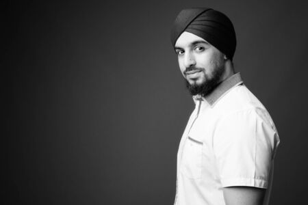 Young bearded Indian Sikh man wearing turban against gray backgroundの写真素材