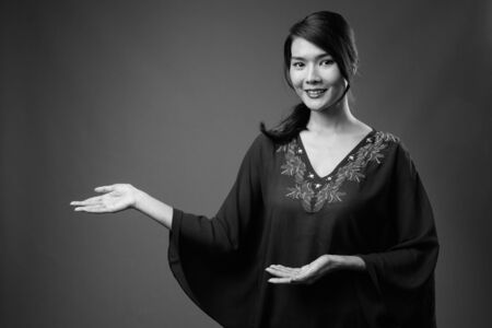 Studio shot of beautiful Asian woman against gray background