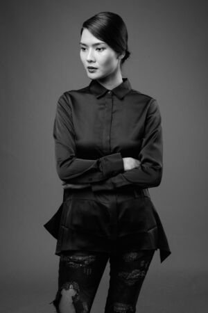 Studio shot of beautiful Asian businesswoman against gray backgroundの写真素材