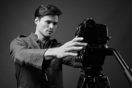 Studio shot of young handsome man vlogging with camera