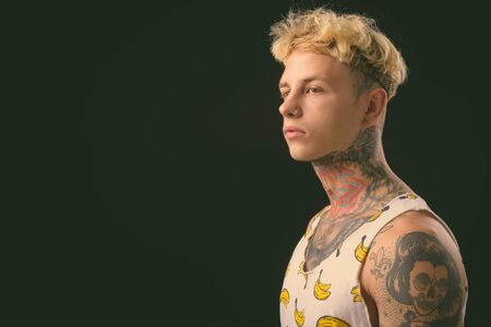 Young handsome rebellious man with blond hair against black background