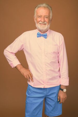 Senior handsome man wearing stylish clothes against brown backgroundの写真素材