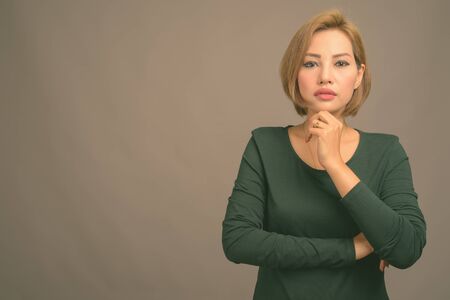 Portrait of beautiful Asian businesswoman against gray backgroundの写真素材