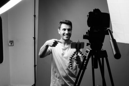 Young handsome Hispanic man vlogging with cameraの写真素材