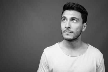 Young handsome Hispanic man against grayの写真素材