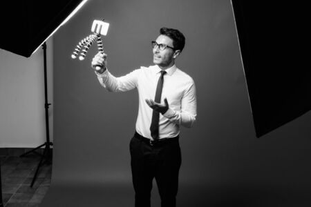 Young handsome Hispanic businessman against grayの写真素材