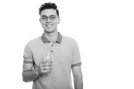 Studio shot of happy young man smiling while holding glass of waterの写真素材