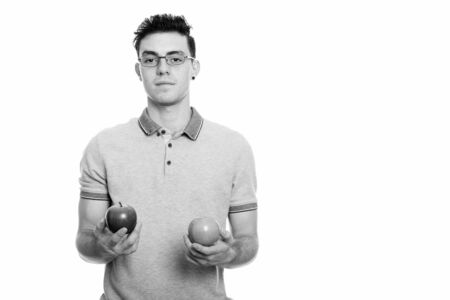 Studio shot of young man holding red and green appleの写真素材