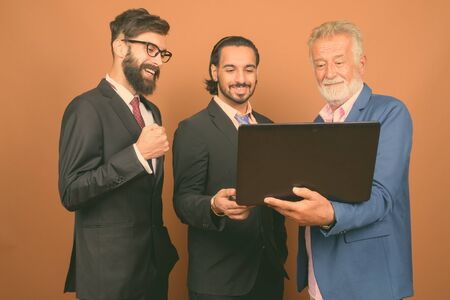 Three multi ethnic bearded businessmen together against brown background