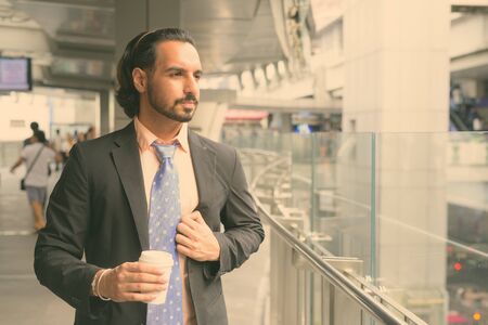 Young bearded Indian businessman relaxing around the cityの写真素材