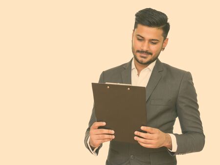 Young handsome bearded Indian businessman with clipboard