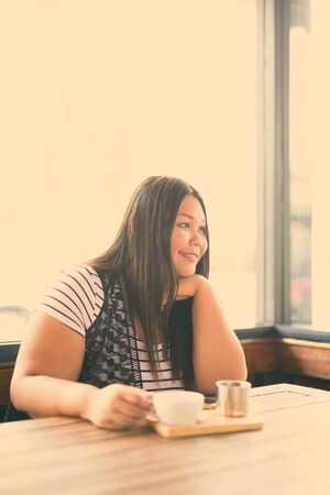 Beautiful overweight Asian woman relaxing at the coffee shopの写真素材