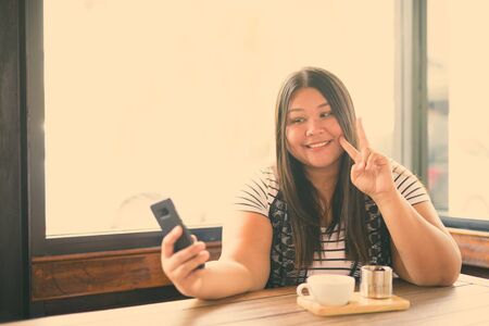 Beautiful overweight Asian woman relaxing at the coffee shopの写真素材