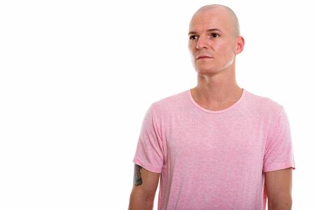 Studio shot of young handsome bald man thinking while looking atの写真素材