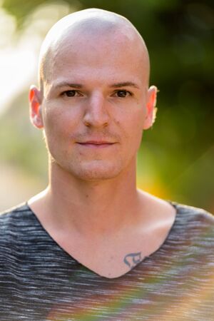 Face of young handsome bald man outdoors