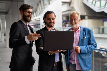 Three multi ethnic bearded businessmen together around the cityの写真素材