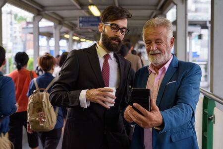 Two multi ethnic bearded businessmen together around the cityの写真素材