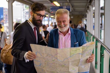 Two multi ethnic bearded businessmen together around the cityの写真素材