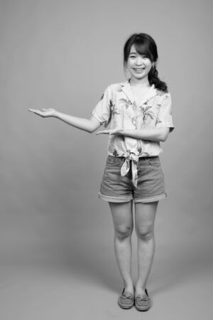 Young beautiful Asian tourist woman ready for vacation against gray backgroundの写真素材