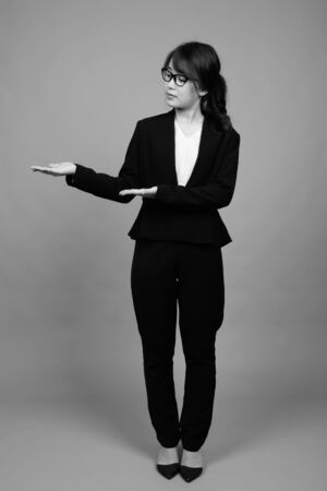 Young beautiful Asian businesswoman against gray backgroundの写真素材
