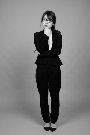 Young beautiful Asian businesswoman against gray backgroundの写真素材