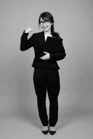 Young beautiful Asian businesswoman against gray backgroundの写真素材