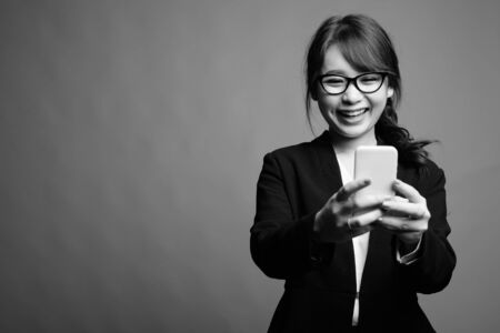 Young beautiful Asian businesswoman against gray backgroundの写真素材